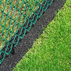 a close up of a green chain link fence with grass in the foreground and black line on the ground