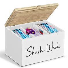 a white wooden box filled with lots of pencils and writing on the lid that says, shark week