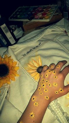 a person with sunflowers painted on their body and hand next to a flower