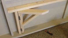 a wooden shelf sitting on top of a floor next to a hammer and screwdriver