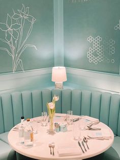 a white table sitting in front of a blue booth with flowers on the wall behind it