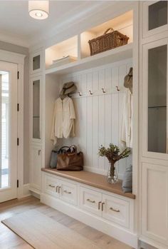 a white entryway with wooden flooring and built - in cabinets