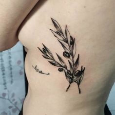 an olive branch tattoo on the side of a woman's stomach