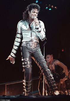 michael jackson performing on stage with his hands in his pockets and holding a microphone to his mouth