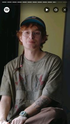 a young man wearing glasses and a baseball cap sitting in front of a computer screen