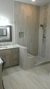 a large bathroom with white tile and marble counter tops on the shower wall, along with two sinks