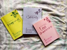 three books sitting on top of a bed next to each other in front of a blanket