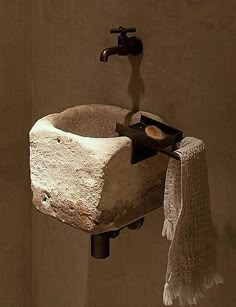 a stone sink mounted to the side of a wall with a towel hanging from it