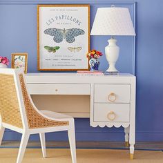 a white desk topped with a lamp next to a blue wall