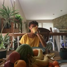 a person sitting at a table with some fruit and drinks in front of them,