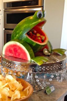 a frog statue sitting on top of a counter next to a bowl filled with chips