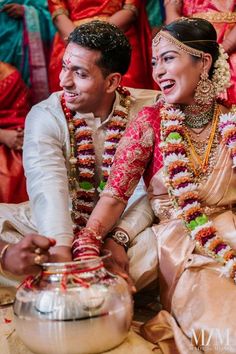 a man and woman sitting next to each other in front of some people wearing colorful outfits