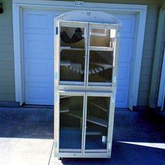 a large bird cage sitting in front of a garage