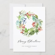 a christmas card with watercolor flowers and greenery on the front, in white