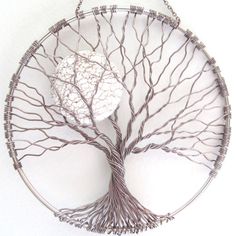 a wire tree sculpture hanging on a wall in the shape of a circular metal object