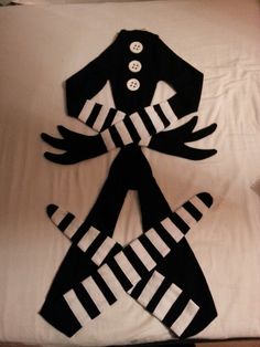 two black and white pieces of clothing on a bed with buttons in the shape of hands