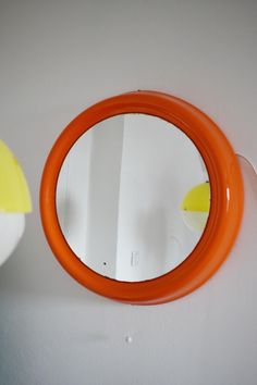 an orange circular mirror hanging on the wall