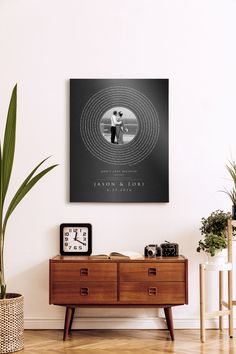 a living room with a large poster on the wall next to a wooden dresser and potted plant