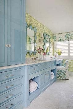 a large bathroom with blue cabinets and white flooring is pictured in this image, there are flowers on the counter