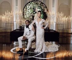 a man and woman posing for a photo in front of a wedding arch with flowers