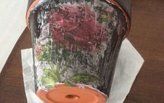 an orange vase sitting on top of a piece of paper with flowers painted on it