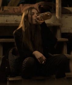 a woman sitting down drinking from a bottle