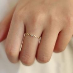 a woman's hand wearing a gold ring with two diamonds on the middle finger