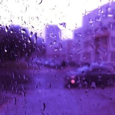 rain drops on a window as cars drive down the street