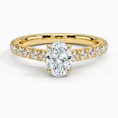 a yellow gold engagement ring with an oval cut diamond in the center and side stones