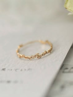 a gold ring sitting on top of a piece of paper next to a white flower