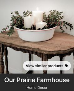 a table with candles and greenery on it in front of a white wall that says our prairie farmhouse