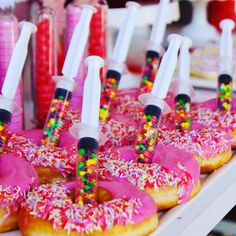 donuts with pink frosting and sprinkles are lined up on a table