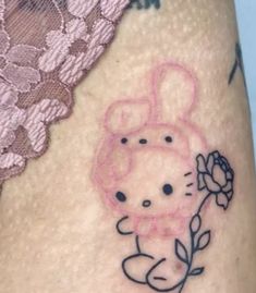 a hello kitty tattoo on the side of a woman's thigh with a flower