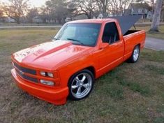 an orange pick up truck parked in the grass