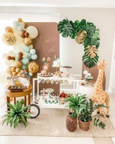 a baby shower is decorated with balloons, jungle plants and giraffes for the party