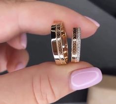 two gold wedding rings with diamonds on each one hand, in front of a woman's finger