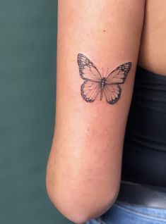 a woman's arm with a small butterfly tattoo on the back of her left arm