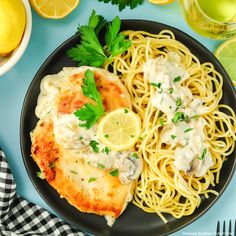 a black plate topped with pasta and chicken