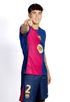 a young man is posing for a photo wearing his soccer uniform and pointing at the camera