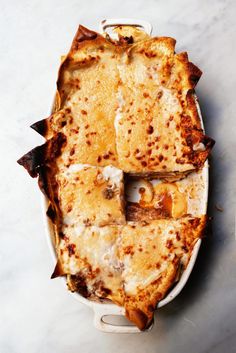 a casserole dish with cheese and other toppings in it on a table