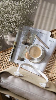 a cup of coffee sitting on top of a table next to a book and bag