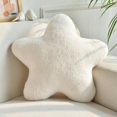 a white star pillow sitting on top of a couch next to a potted plant