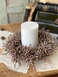 a white candle sitting on top of a table next to some old books and papers