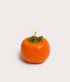 a tomato with a candle in it on a white surface