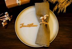 a white plate topped with a napkin next to a brown box and some dried flowers