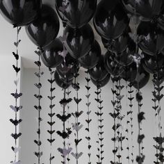 black balloons are hanging from the ceiling in front of a wall with flowers on it