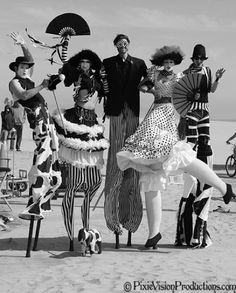 a group of people standing on top of a beach next to each other wearing costumes