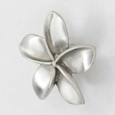 a silver flower brooch sitting on top of a white table