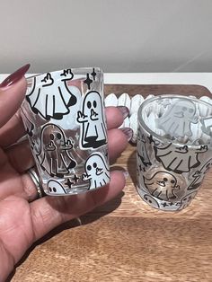 a person holding two glass cups with designs on them