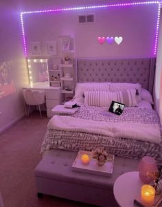 a bed room with a neatly made bed and purple lights on the wall above it